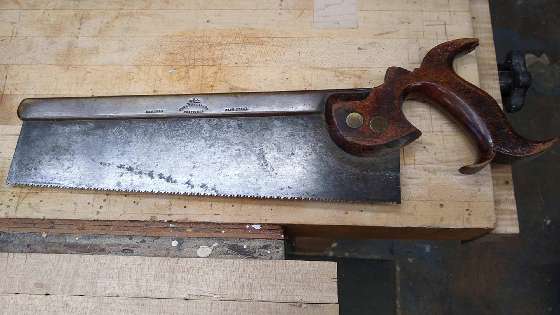 一只旧的手锯与木把柄。“title=