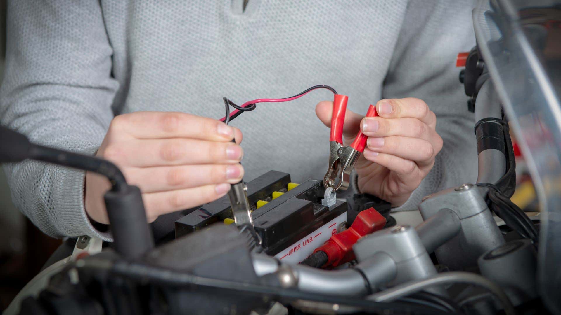 一个男士将电荷电缆连接到摩托车电池。