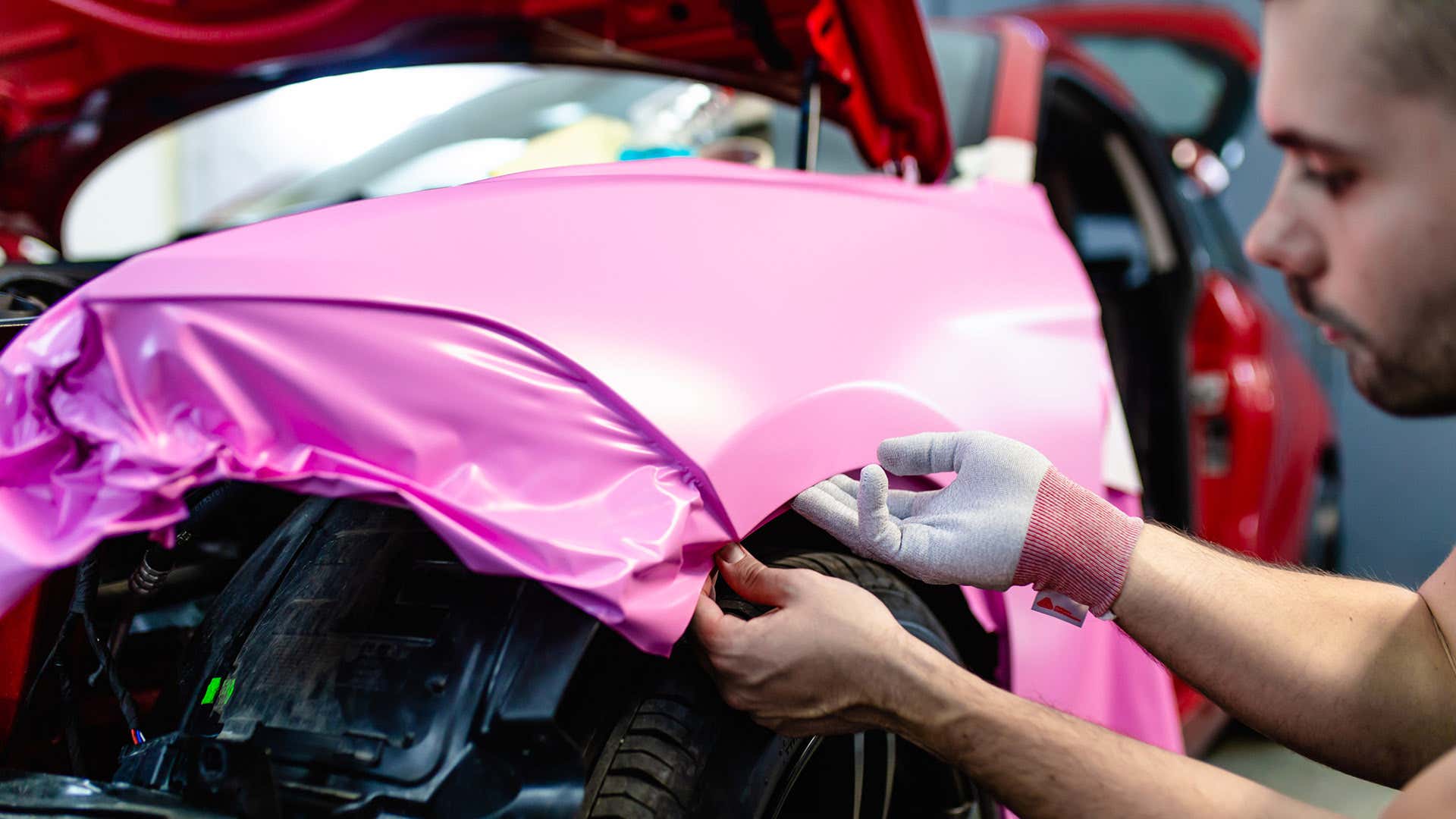 安装人员使用无关的手套将乙烯基包裹涂给汽车。