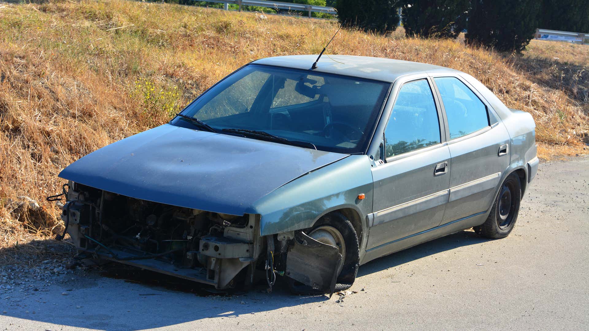 一个没有前端的被破坏的汽车坐在路边。