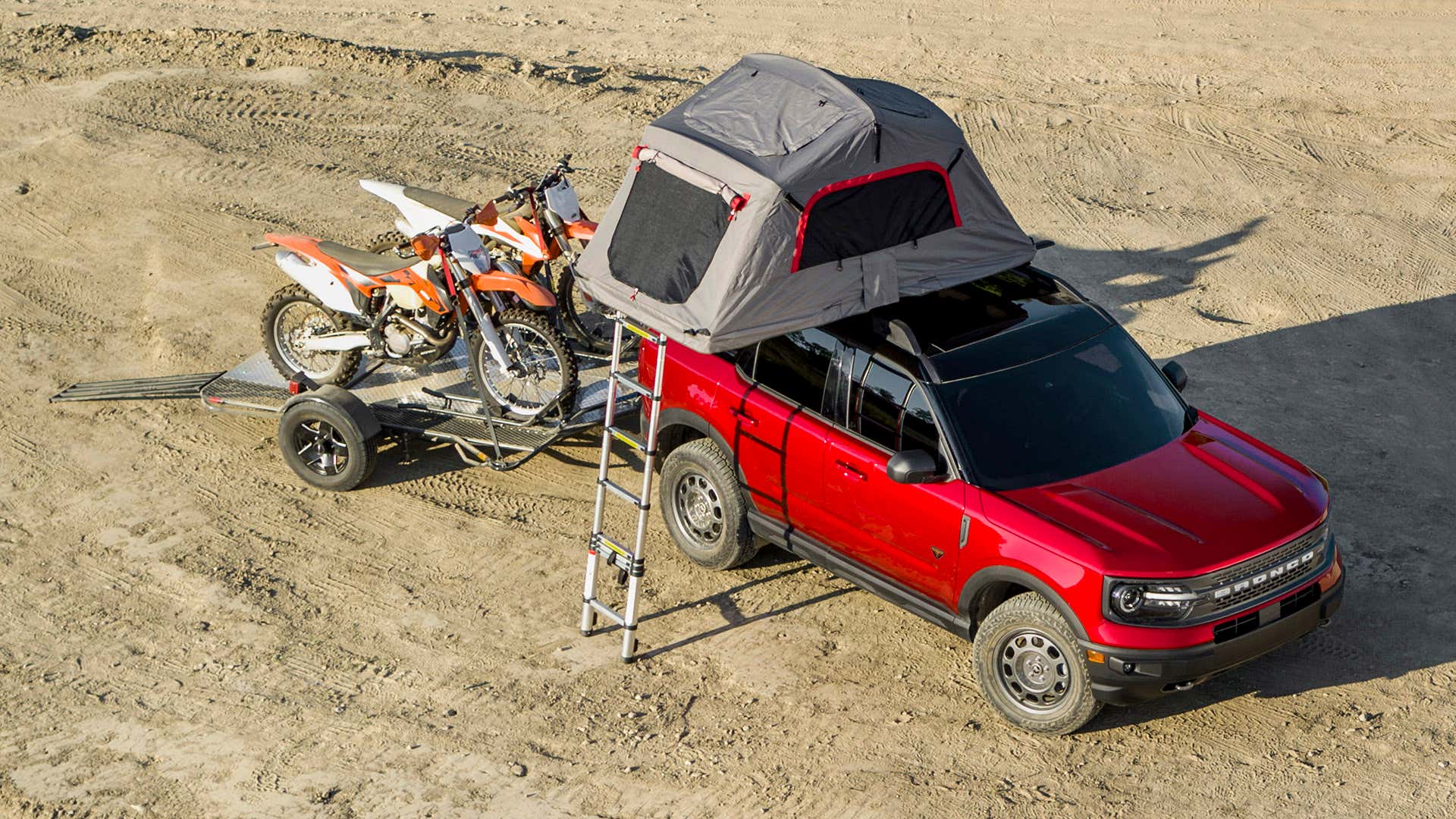 与屋顶帐篷的红色福特Bronco体育拉扯在拖车上的两个土地骑自行车。